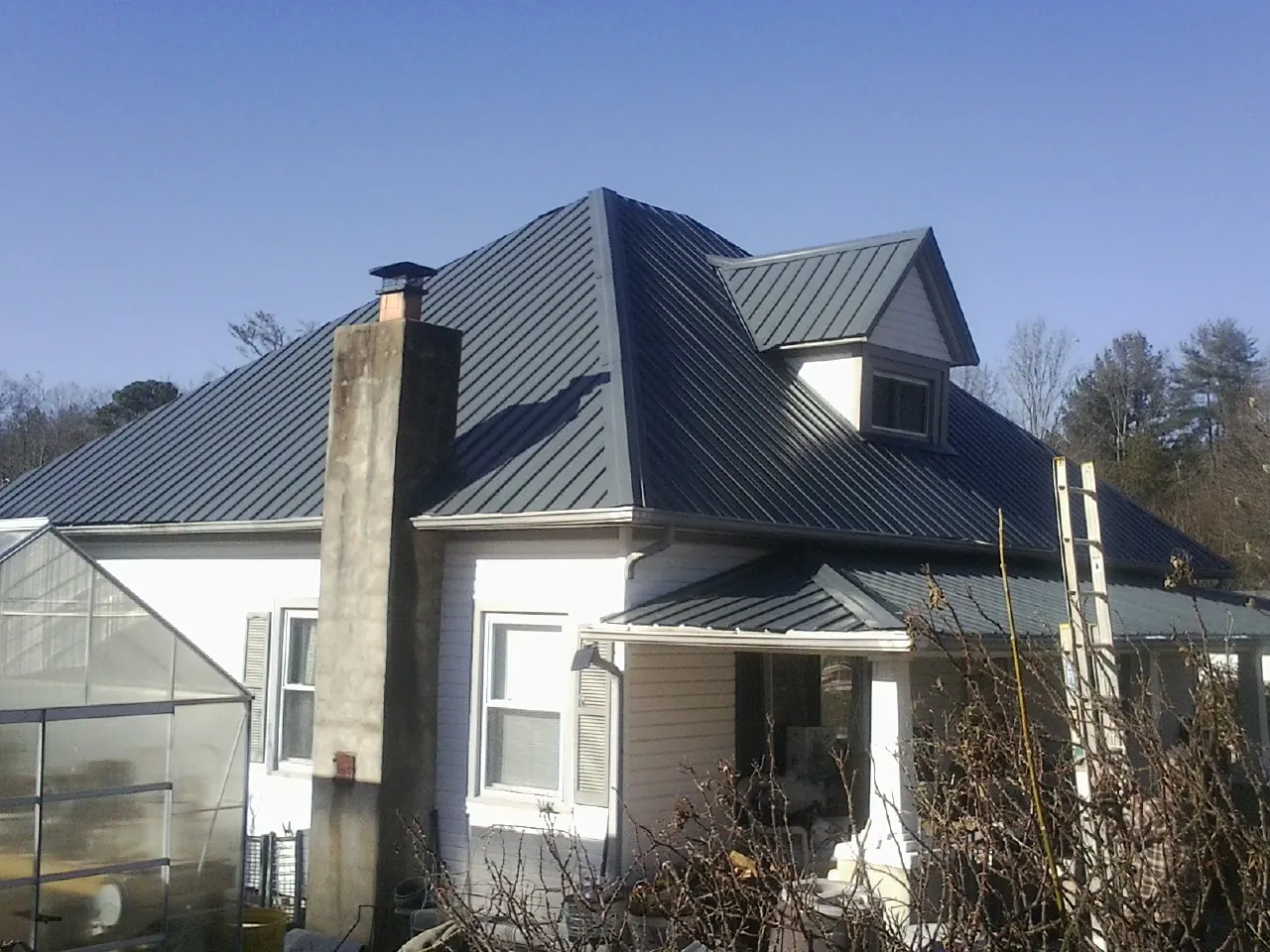 Dark blue standing seam metal roof on a white farmhouse with dormer — Slate & Tile Roof Repair by Roofing Brothers in Gordonsville
