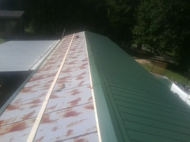 Old rusted panels beside newly installed green metal roofing — Wind Damage Roof Repair by Roofing Brothers in Gordonsville