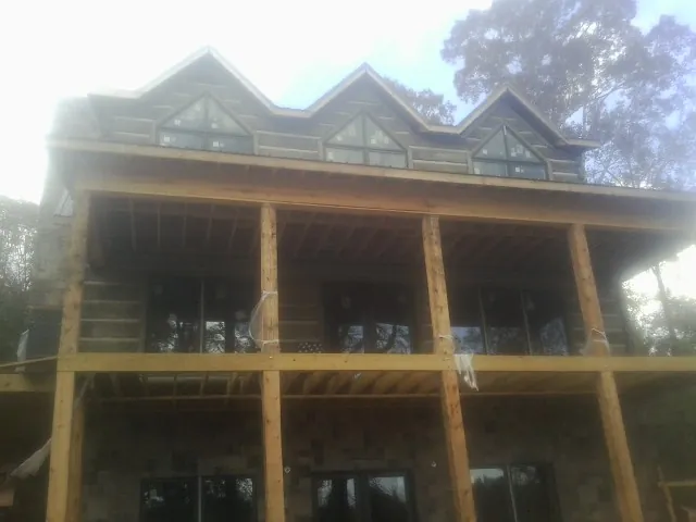 Dormers and porch framing on a large log home under construction — Roof Coating work by our crew in Gordonsville