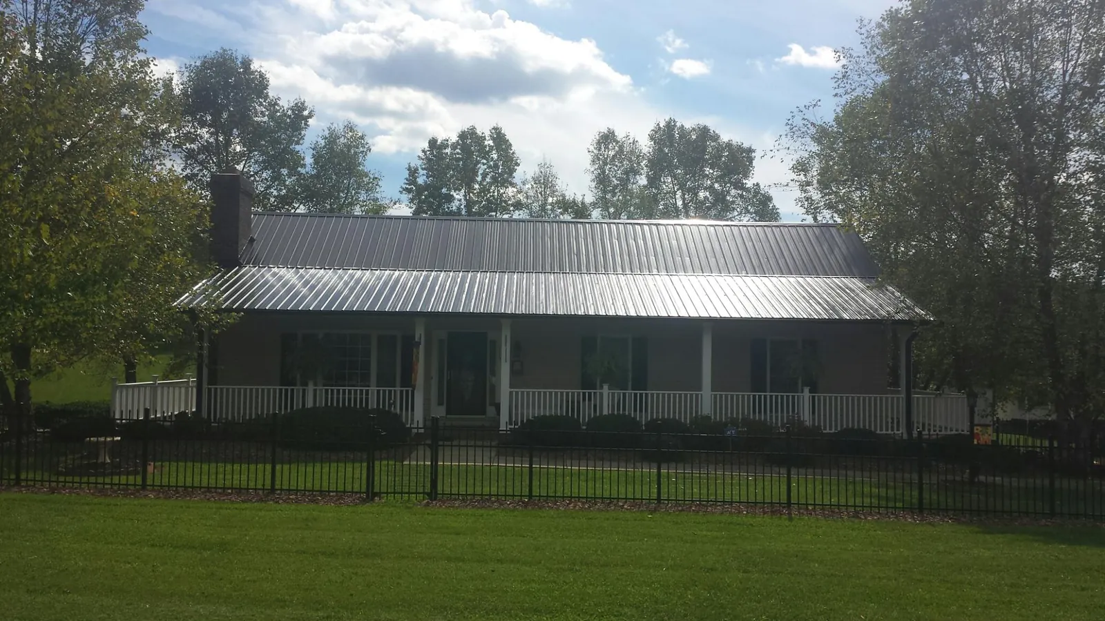 Gray metal roof on a brick ranch with a full width front porch — Gutter Guard Installation work by our crew in Gordonsville
